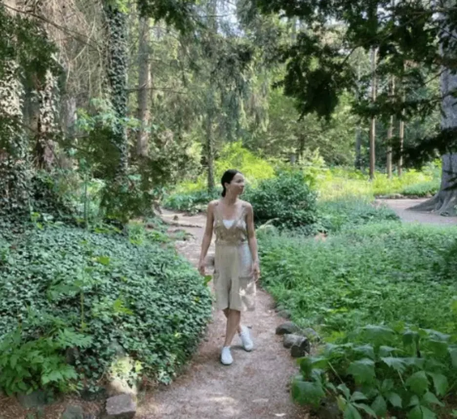 Kobieta w lnianym kombinezonie wśród zieleni Parku Oliwskiego w Gdańsku