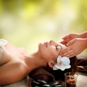 Kobieta w SPA, podczas masażu twarzy. Zrelaksowana buzia i kwiat we włosach.